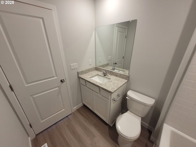 bathroom with vanity, wood finished floors, toilet, and baseboards