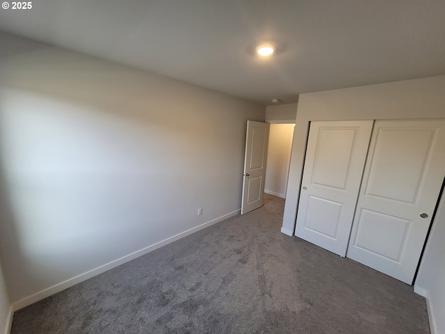 unfurnished bedroom with carpet, a closet, and baseboards