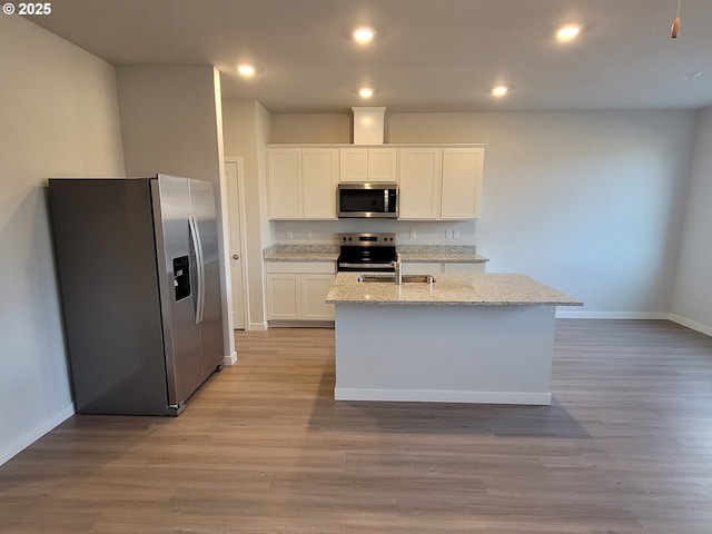 kitchen featuring light wood-style floors, appliances with stainless steel finishes, white cabinets, and a sink