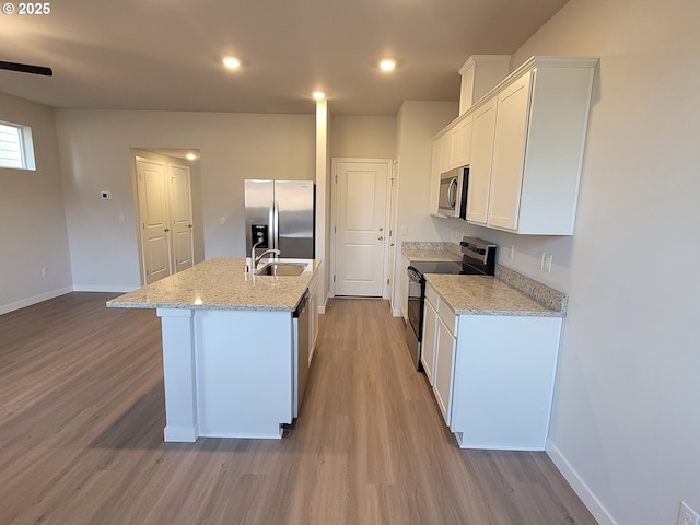 kitchen featuring stainless steel appliances, light wood-style floors, white cabinets, and a sink