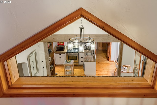 room details with stainless steel range oven, a chandelier, and hardwood / wood-style floors