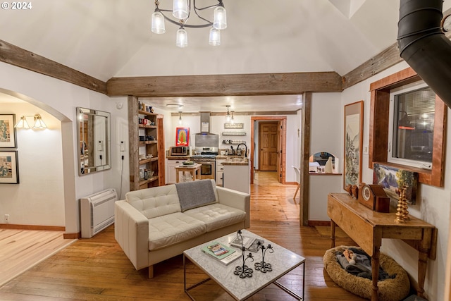 living room featuring an inviting chandelier, light hardwood / wood-style flooring, a wood stove, and lofted ceiling