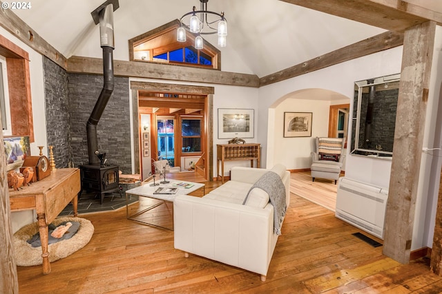 living room featuring a notable chandelier, high vaulted ceiling, radiator, light hardwood / wood-style floors, and a wood stove