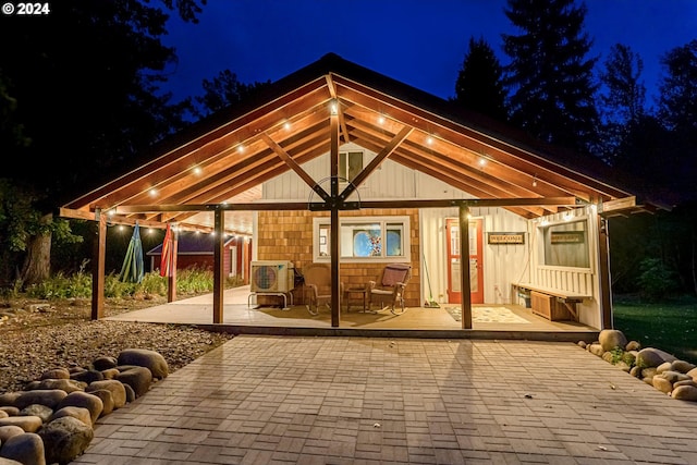 back house at night featuring a gazebo and a wooden deck