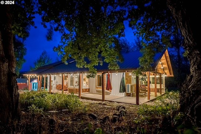 back house at twilight with a wooden deck