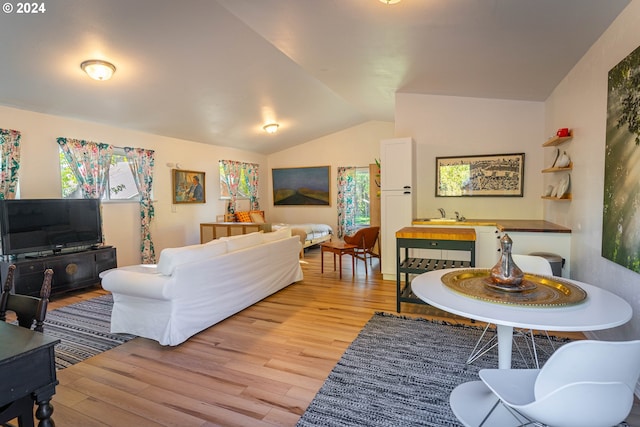 living room featuring sink, vaulted ceiling, and light hardwood / wood-style floors