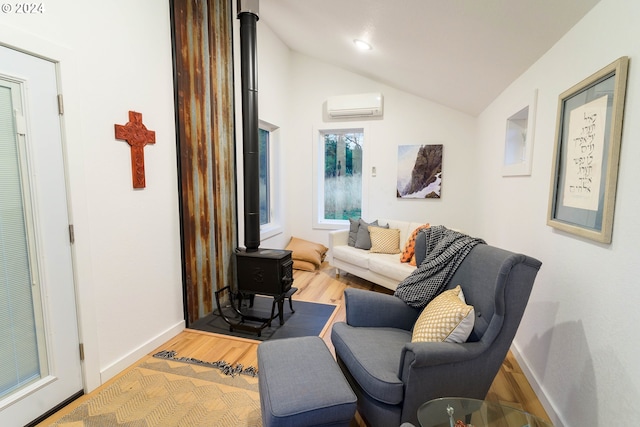 sitting room with light hardwood / wood-style flooring, a wood stove, a wall mounted air conditioner, and vaulted ceiling