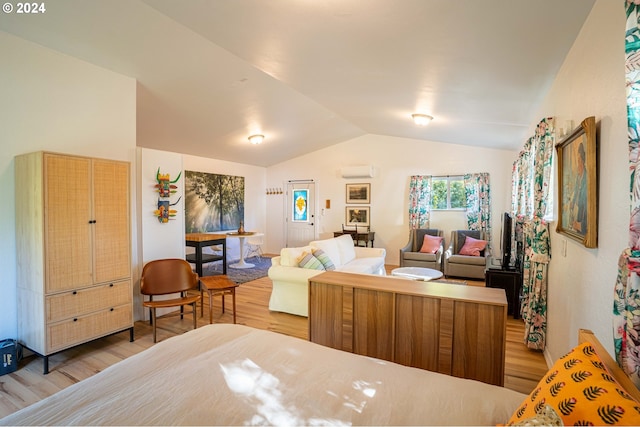 bedroom featuring an AC wall unit, lofted ceiling, and light wood-type flooring