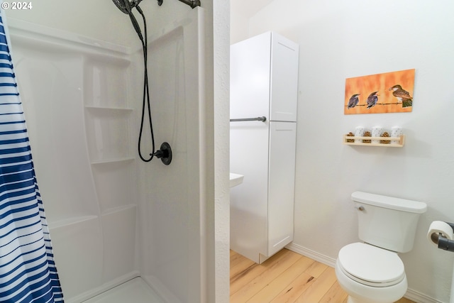 bathroom with curtained shower, wood-type flooring, and toilet