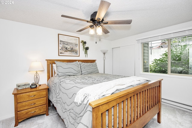 carpeted bedroom featuring ceiling fan, a textured ceiling, and a baseboard heating unit