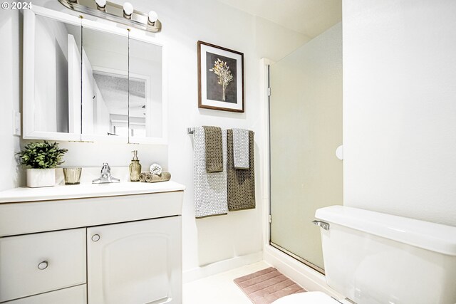 bathroom with tile patterned floors, vanity, toilet, and a shower with shower door