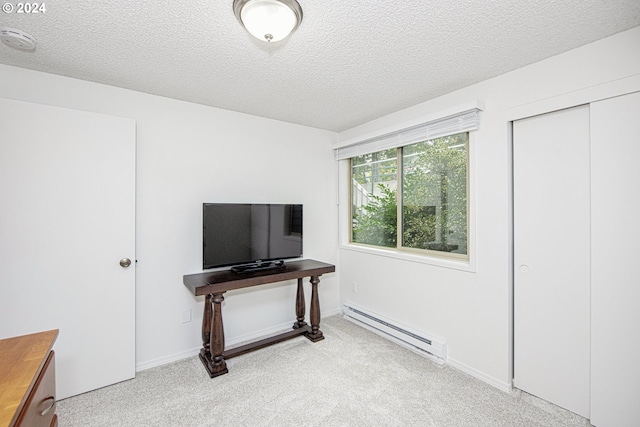 bedroom with a closet, a baseboard heating unit, a textured ceiling, and light carpet