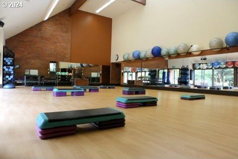 workout area featuring high vaulted ceiling and wood-type flooring