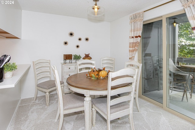 dining area featuring light colored carpet and a textured ceiling