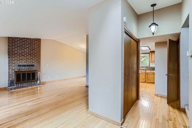 corridor featuring light wood-type flooring and vaulted ceiling