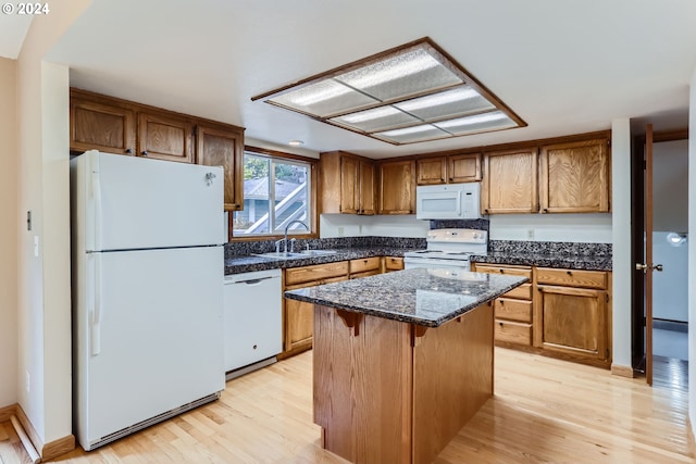 kitchen featuring a center island, sink, dark stone countertops, light hardwood / wood-style floors, and white appliances