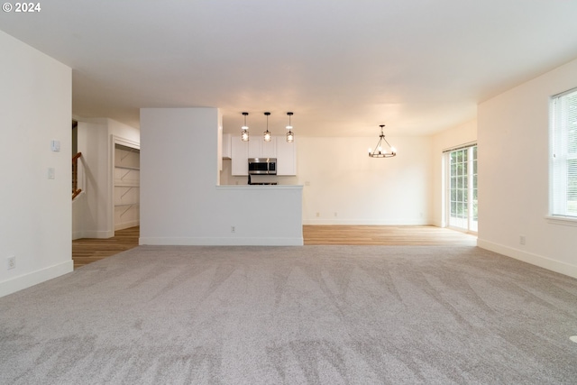 unfurnished living room with a chandelier and light colored carpet