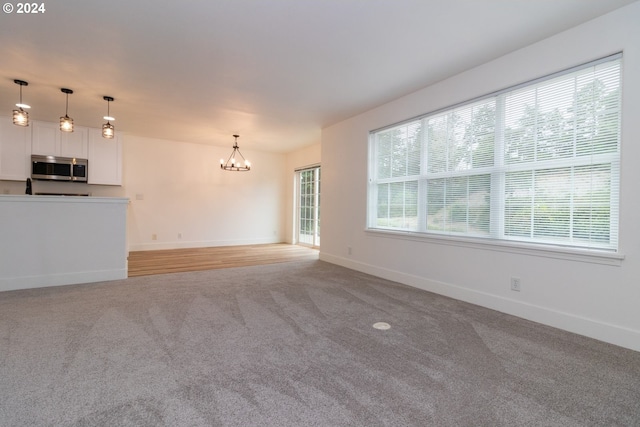 unfurnished living room with light carpet and a chandelier