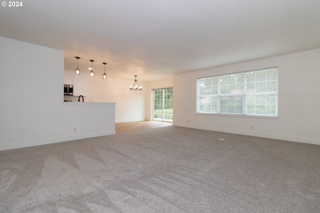 carpeted spare room with sink and a chandelier