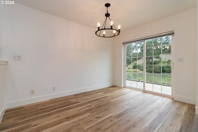 spare room with hardwood / wood-style floors and a notable chandelier