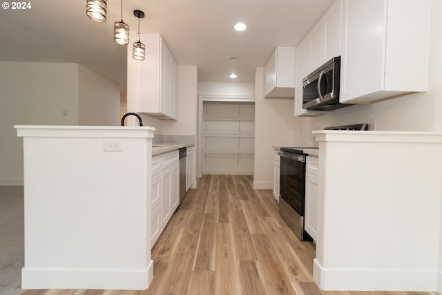 kitchen with stainless steel appliances, white cabinets, sink, light hardwood / wood-style floors, and decorative light fixtures