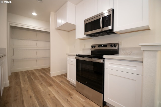 kitchen with white cabinets, stainless steel appliances, and light hardwood / wood-style floors