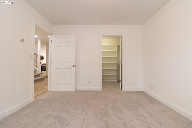 unfurnished bedroom with light colored carpet, a closet, and a walk in closet