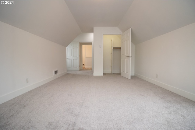 additional living space featuring light colored carpet and lofted ceiling