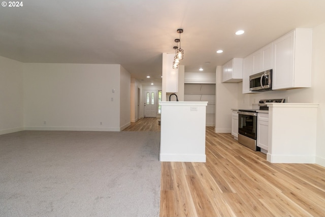 kitchen with pendant lighting, white cabinetry, stainless steel appliances, and light hardwood / wood-style flooring