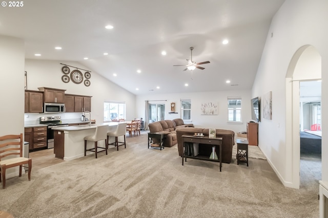 carpeted living room featuring ceiling fan, sink, and high vaulted ceiling