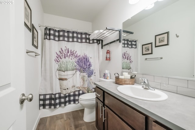 bathroom featuring hardwood / wood-style flooring, vanity, toilet, and curtained shower