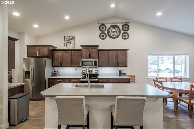 kitchen with hardwood / wood-style flooring, stainless steel appliances, sink, and a center island with sink