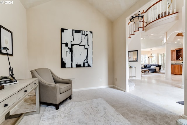 living area with arched walkways, decorative columns, light colored carpet, high vaulted ceiling, and baseboards