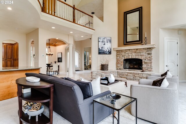 living room with a fireplace, ornate columns, and a towering ceiling