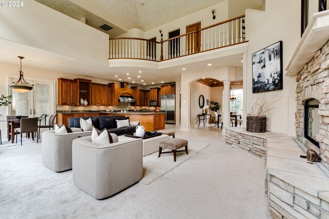 carpeted living room with a high ceiling and a stone fireplace