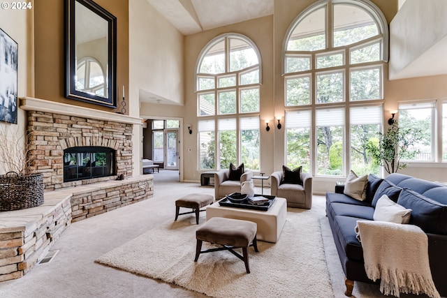 living room featuring a stone fireplace, a towering ceiling, and light colored carpet