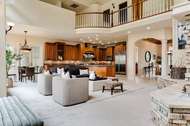 living area featuring a towering ceiling, visible vents, decorative columns, and arched walkways