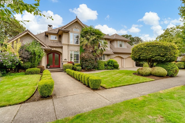 view of front facade featuring concrete driveway, stucco siding, a chimney, french doors, and a front yard