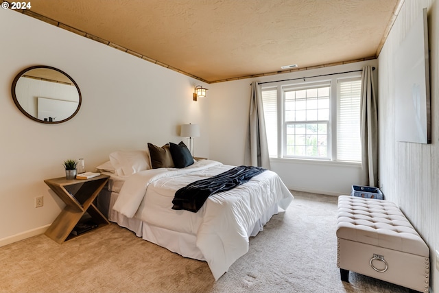 bedroom with baseboards, a textured ceiling, and light colored carpet