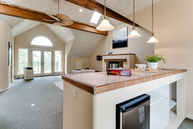 kitchen featuring french doors, beam ceiling, tile counters, carpet, and pendant lighting