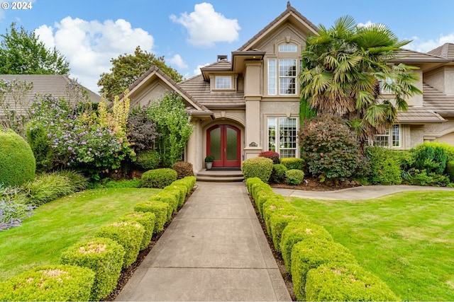 view of front facade with french doors, a front yard, and stucco siding