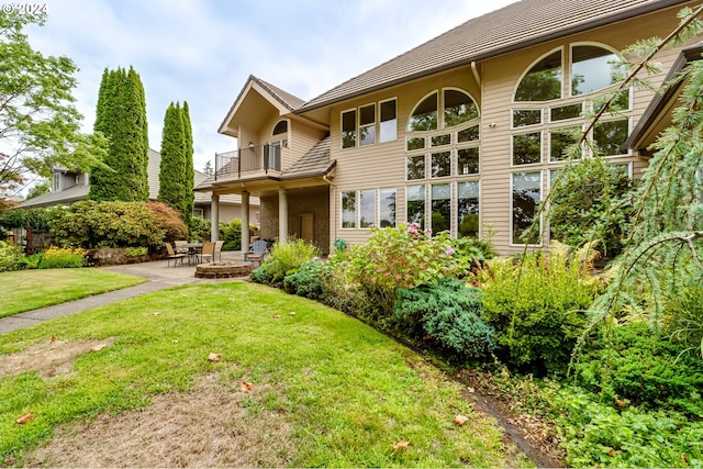 back of property featuring a yard, a patio, and a balcony