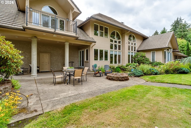 back of house featuring an outdoor fire pit, a lawn, a patio area, and a balcony