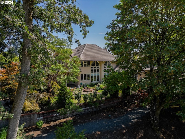 rear view of house featuring a tile roof and fence