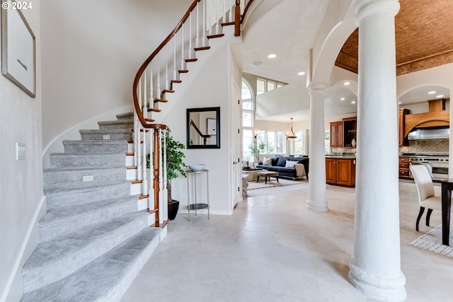 entrance foyer with stairway, a towering ceiling, decorative columns, and recessed lighting