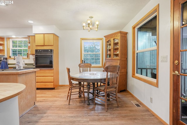 dining space featuring light wood-type flooring and a notable chandelier