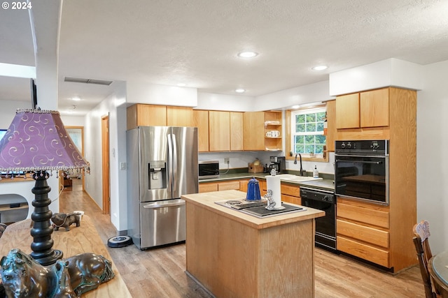 kitchen featuring sink, light hardwood / wood-style flooring, a textured ceiling, a kitchen island, and black appliances