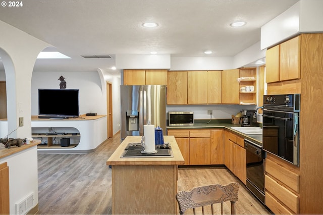 kitchen featuring wood counters, black appliances, sink, light wood-type flooring, and a kitchen island