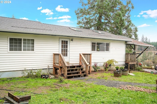 rear view of property featuring a wooden deck and a yard