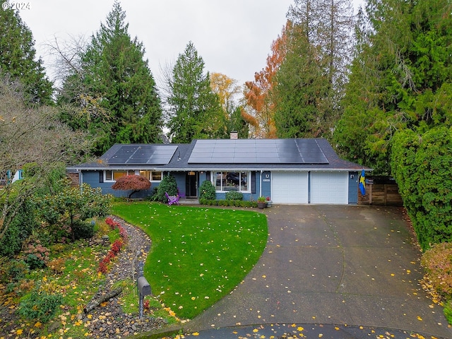 single story home with solar panels, a garage, and a front lawn